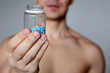 Man with pills, bottle with blue tablets in male hands close up. Muscular guy in with naked torso, concept of viagra, medication for stomach, erection