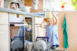 © Irina Schmidt - Little adorable cute toddler girl helping to unload dishwasher. Funny happy child standing in the kitchen, holding dishes and putting a bowl on head. Healthy kid at home. Gorgeous helper having fun