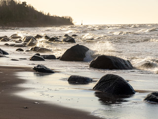 backlit landscape with stony sea shore