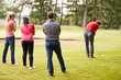 Golf Professional Demonstrating Shot On Fairway To Group Of Golfers During Lesson