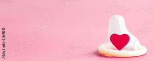 Fotomural open condom and a red little heart on a pink background, place for text