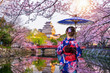 © tawatchai1990 - Asian woman wearing japanese traditional kimono looking at cherry blossoms and castle in Himeji, Japan.
