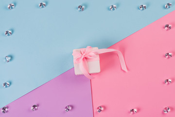 Canvas Print - Small gift wrapped pink ribbon with crystals on pink blue background. Holiday background. Minimal concept. Flat lay. Top view.