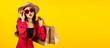 © ChayTee - Banner of Asian trendy shopaholic woman excited about new purchases or sales holding shopping bags and looking to camera over yellow background. Happy Asian customer carrying shopping bags.