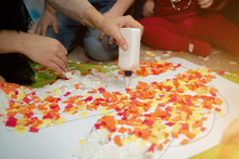 Children Are Engaged In Creativity. Multi-colored Pieces Of Paper Cut Into Squares In The Hands Of Children