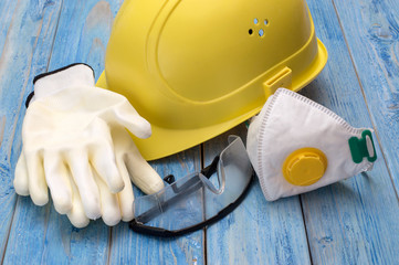 helmet gloves and glasses for construction work on a wooden background.