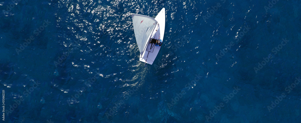 Aerial drone ultra wide photo of children practising with small sail boats in Mediterranean bay with deep blue sea - obrazy, fototapety, plakaty 
