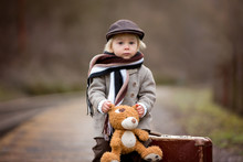 Adorable Boy On A Railway Station, Waiting For The Train With Suitcase And Sweet Teddy Bear