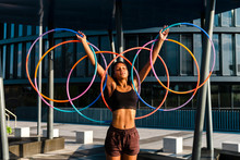 Generation Z Young Woman Holding Five Hula Hoop In Downtown At Sunset
