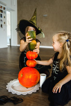 Two Sisters Dressed For Halloween In Skeleton Costumes With Pumpkins