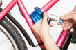© Kekyalyaynen - Human arms fastening the bike lock on pink frame, cable lock with key, white background