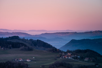 Canvas Print - village between hills in switzerland with red sky and warm light during blue hour in winter