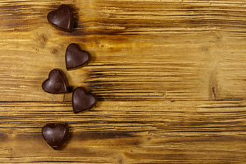 Wall Mural - Heart shaped chocolate candies on wooden background. Top view, copy space. Valentine Day concept