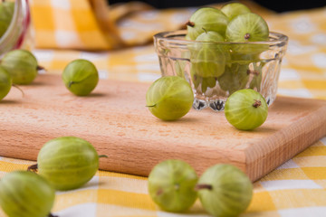 Green cherry-plums on a wooden board. Fruits in a glassware. Close-up.