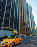 Fototapeta Miasta - Yellow taxi on road. Street view in Financial District of Lower Manhattan, New York of USA. Skyline and cityscape with skyscrapers at United States of America, NYC, US. American architecture.
