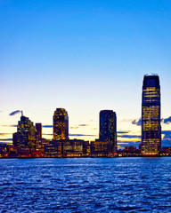 Wall Mural - Night Jersey City, New Jersey and Hudson River. View from Manhattan, New York of USA. Skyline and cityscape with skyscrapers at United States of America, NYC, US. Road and American architecture.