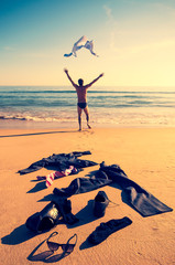 Excited businessman throwing his business clothes in the air on the shore of the beach running to the sea