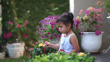 Wall Mural - Cute little girl playing bubbles in garden.