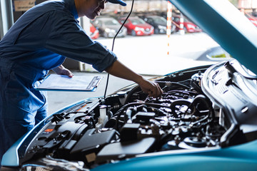 Wall Mural - Car mechanic holding clipboard and checking to maintenance vehicle by customer claim order in auto repair shop garage. Engine repair service. People occupation and business job. Automobile technician