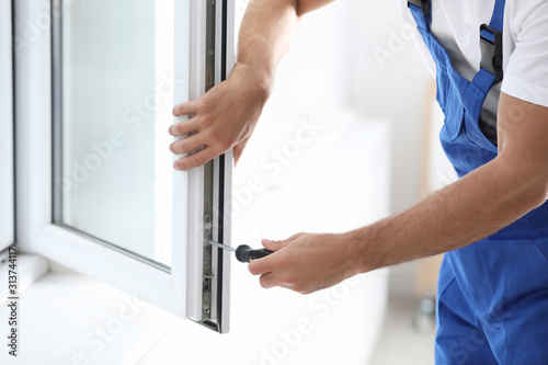 Fotomural Construction worker repairing plastic window with screwdriver indoors, closeup
