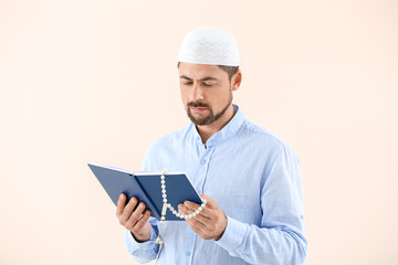 Wall Mural - Muslim man with Koran and beads on light background