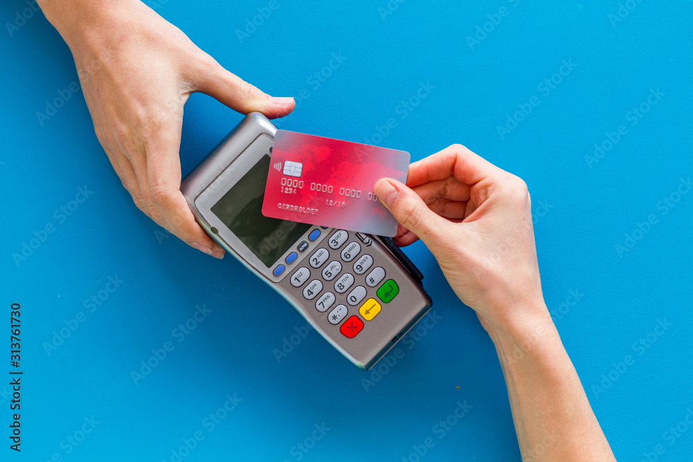 Contactless payment, paypass. Hand hold bank card near terminal on blue ...