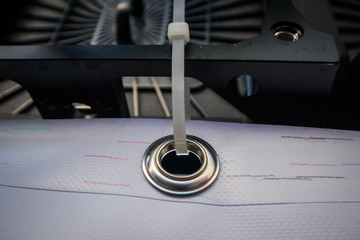 Metal ring or grommet on a vinyl banner, secured with a zip tie. Riveted steel eyelet used for hanging banners, detail with a zip tie.