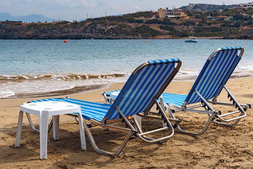 two sun loungers on the sandy beach of the Greek resort town of Agios Nikolaos