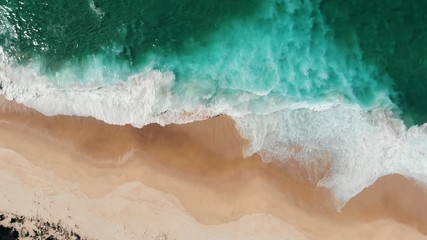 aerial view of drone flying above beautiful beach with views of ocean waves and water crashing on to