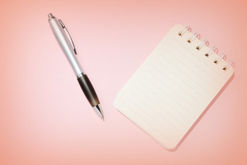 Lined notebook and pen on a pink background close-up. Top view, copy space. Education concept retro style toned