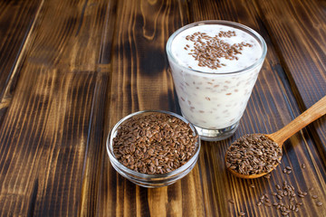 Wall Mural - Yogurt or kefir with flax seeds in the glass on the brown wooden  background. Copy space.