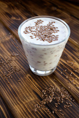 Wall Mural - Yogurt or kefir with flax seeds in the glass on the brown wooden  background. Location vertical. Copy space.