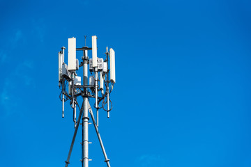 Communication tower with antennas on the top of building and bright blue sky background.