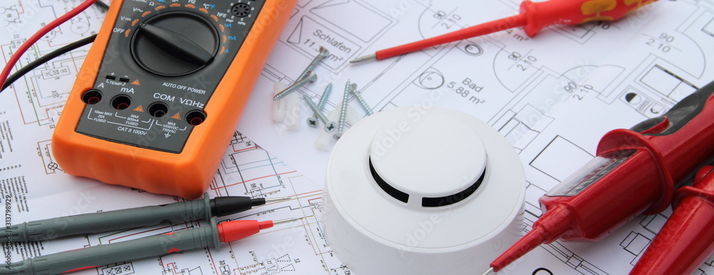 smoke detector with a screwdriver and a measuring device on a circuit diagram - obrazy, fototapety, plakaty 