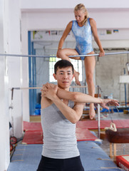 Wall Mural - Man gymnast training gymnastic action at gym, woman on background