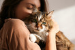 canvas print picture - Portrait of young woman holding cute siberian cat with green eyes. Female hugging her cute long hair kitty. Background, copy space, close up. Adorable domestic pet concept.