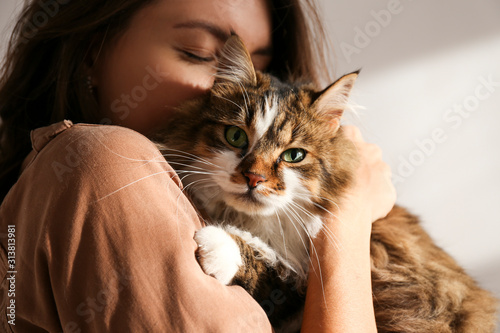 Photographie Portrait of young woman holding cute siberian cat with green eyes