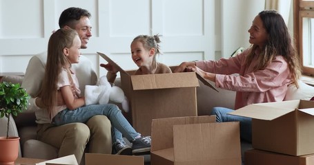 Wall Mural - Cute kid daughter jumping out of box on moving day