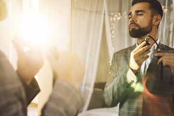 Wall Mural - Handsome bearded man is using atomizer nozzle with perfume