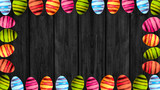 Fototapeta Tulipany - Happy Easter background - Frame made of colorful painted eggs isolated on dark rustic wooden texture, with space for text