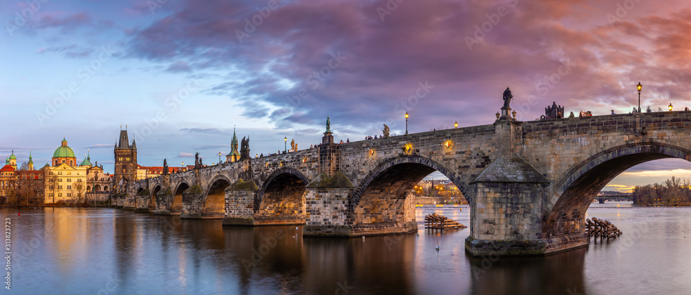 Prague, Czech Republic - Panoramic view of the world famous Charles Bridge (Karluv most) and St. Francis Of Assisi Church on a winter afternoon with beautiful purple sunset and sky - obrazy, fototapety, plakaty 