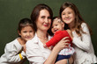 © Gecko Studio - Happy young family with three child smiling at camera, close-up