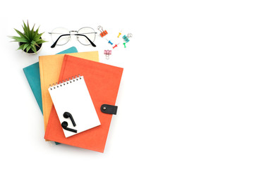 Wall Mural - Work space education and back to school concept on white modern table desk with stack of book and blank note pad, earphone, green plant and paper clip, flat lay, Top view with copy space