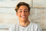 close up of beautiful teenager smiling and laughing alone at home - portrait of face of young man