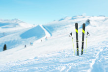 Skis And Poles Pinned Into The Snow. Ski Slope In The Background. Concept Of Alpine Skiing And Active Sports