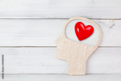 Human Head and Red Heart inside brain shape over white wood background. Symbol for falling or being in love, liking, emotions and affection Concept with copy space.