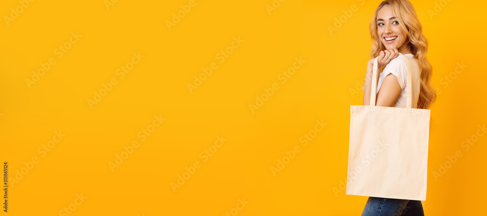 Beautiful blonde girl with tote bag over yellow background, long banner - obrazy, fototapety, plakaty 