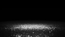 Silver Glitter Twinkling On A Surface Lit By A Bright Spotlight In Front Of A Black Background
