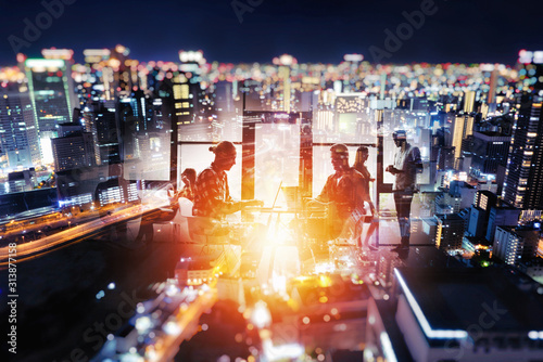 Fotomural Silhouette of young business people work together in office at night on a skylin