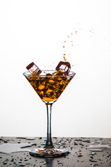 Colorful Liquid Droplets With Ice Cubes Falling to Goblet. Against White Background.